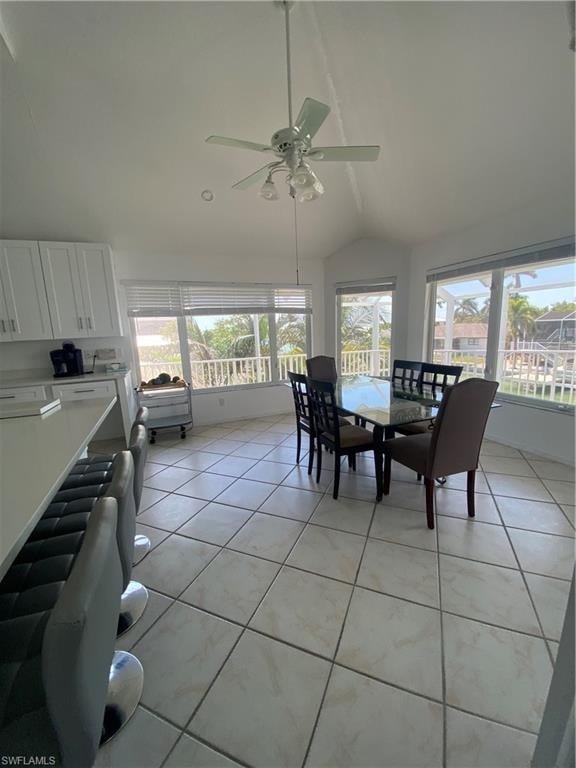 Dining space featuring lofted ceiling, light tile patterned flooring, radiator heating unit, and a ceiling fan
