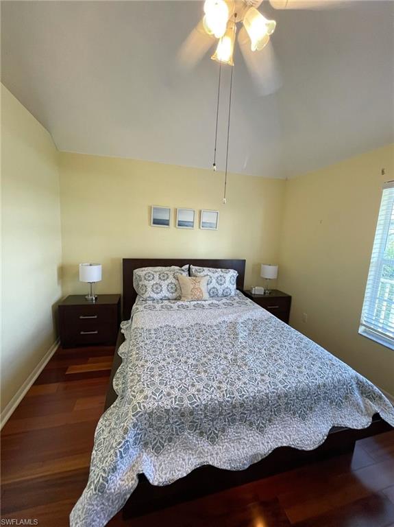 Bedroom with lofted ceiling, dark wood-type flooring, and ceiling fan