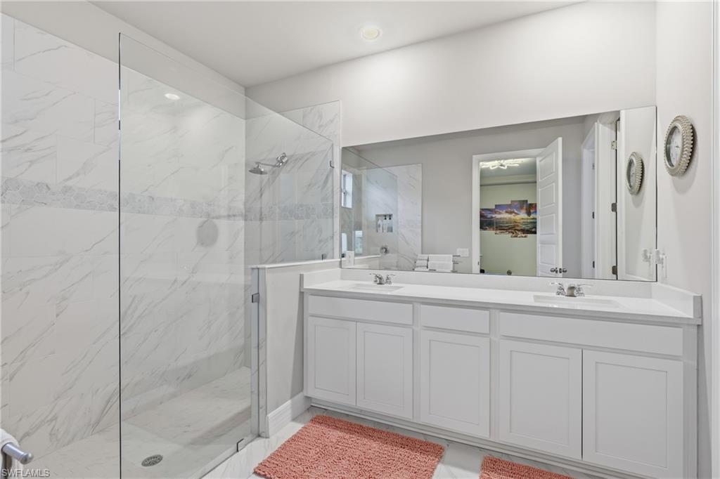 Luxurious primary bath with dual sinks, quartz countertops an a large frameless glass walk in shower