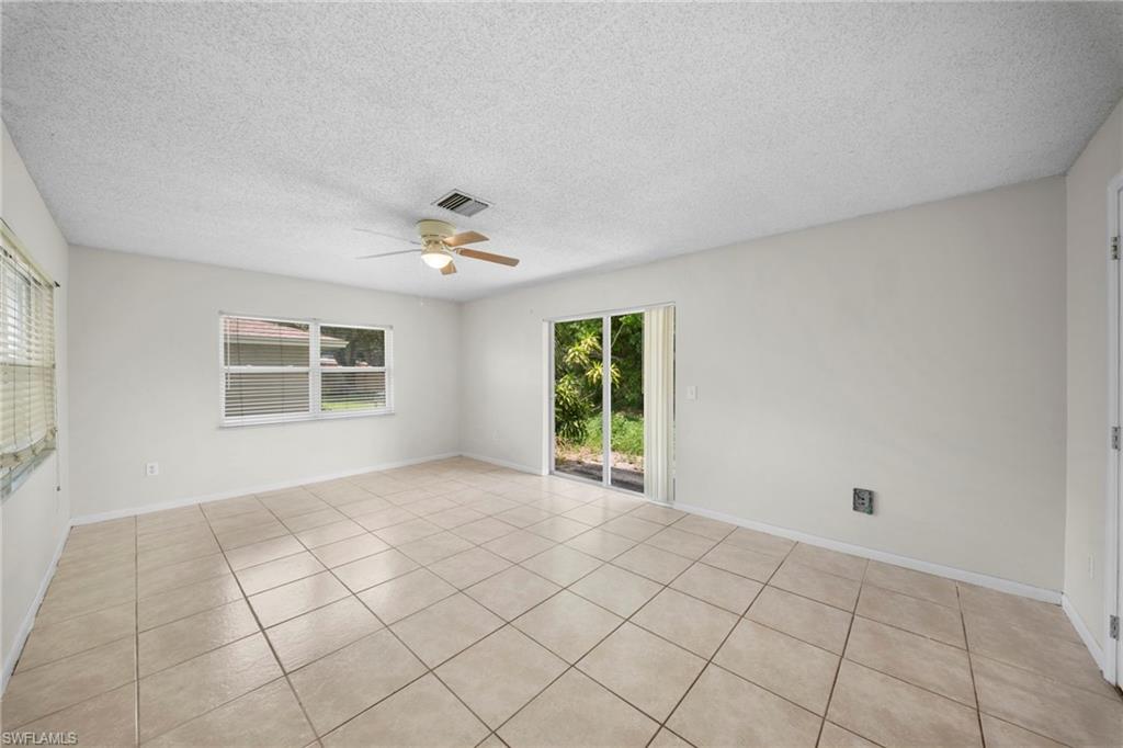 Spacious room with light-toned tiled flooring, a ceiling fan, and sliding glass doors