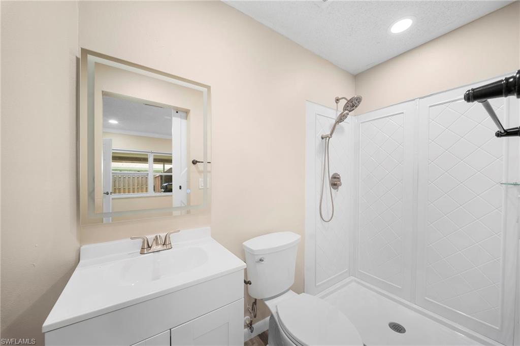 White vanity with integrated sink, brushed nickel faucet, and frameless backlit mirror