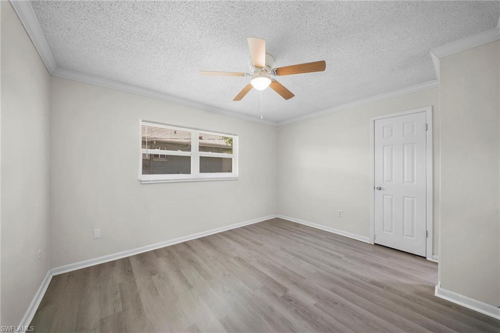 Bright, spacious bedroom showcasing wood-finish flooring, fresh neutral walls, and abundant natural light from dual windows