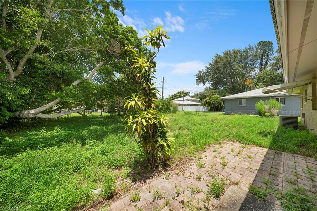 Expansive outdoor area featuring mature trees and a paved patio