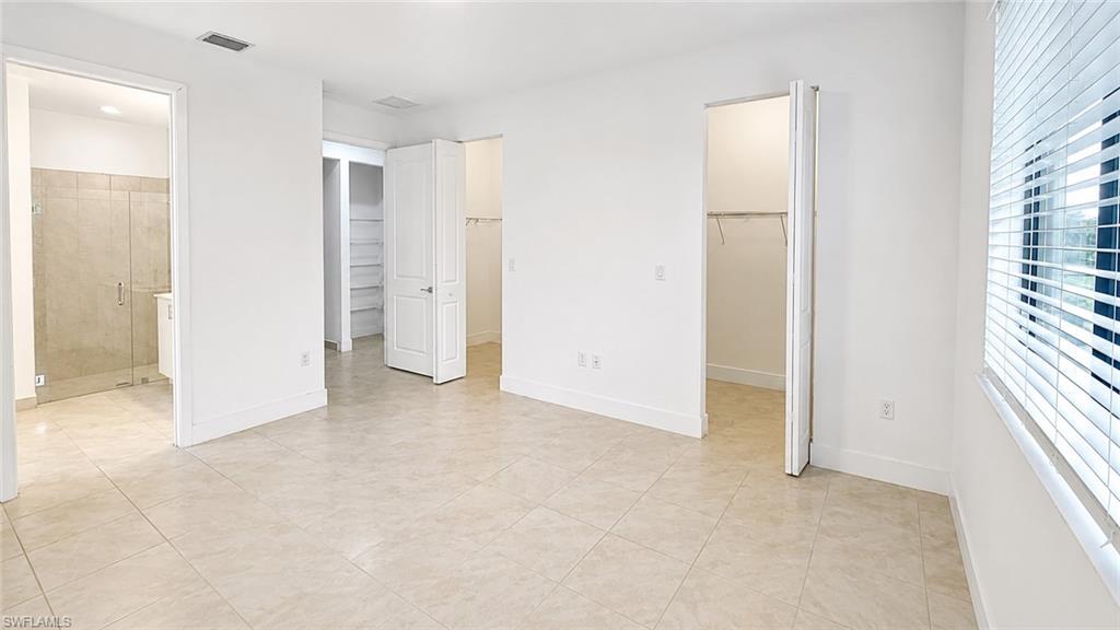 Light-toned tile flooring, white walls, and a window with blinds