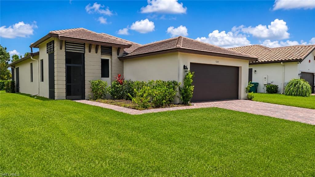 Stucco exterior residence with a tiled roof, paver driveway, and an attached garage