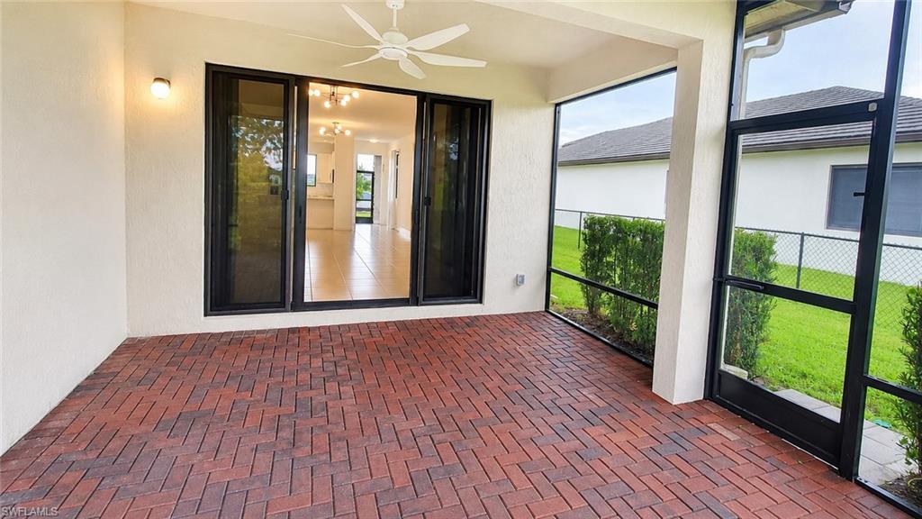 Expansive screened-in lanai featuring brick paver flooring, a ceiling fan, and sliding glass doors