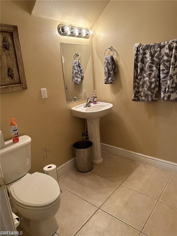 Pedestal sink with chrome faucet, wall-mounted mirror, and vanity lighting