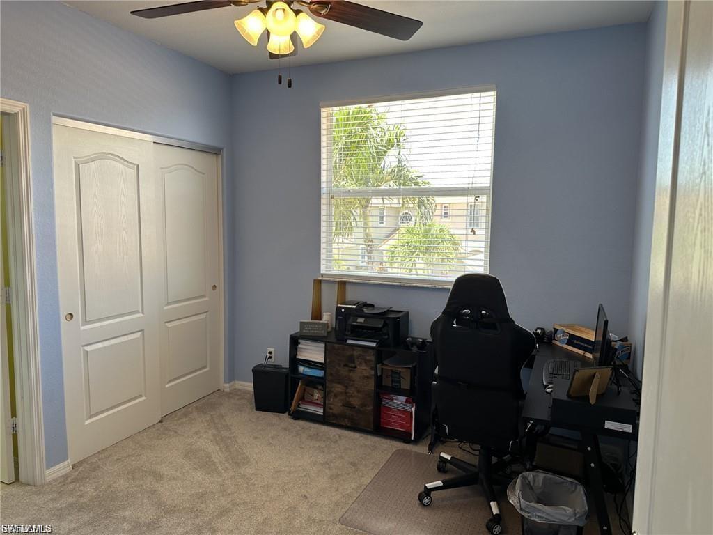 Room featuring light blue walls, carpet flooring, a window with blinds, and a ceiling fan with integrated lighting