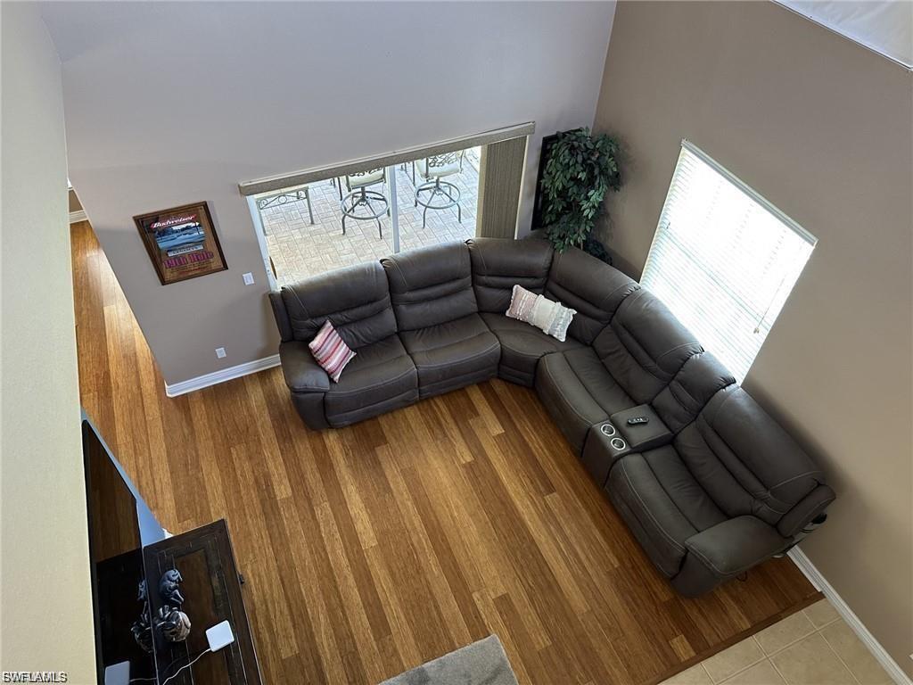 Vaulted ceiling, wood-finish flooring, sliding glass doors, window blinds, and neutral wall tones