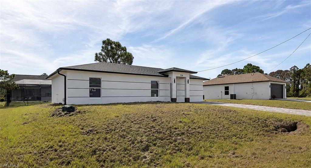 Contemporary-style exterior with white stucco finish, dark shingle roof, paved driveway, and detached garage structure