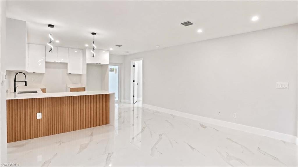 Kitchen featuring white cabinetry, a large island with wood-finish paneling, white countertops, and a black gooseneck faucet