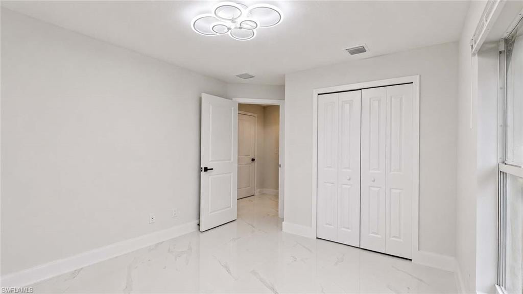 Bright room featuring white walls, white bi-fold closet doors, white door with black hardware, and a modern ceiling light fixture