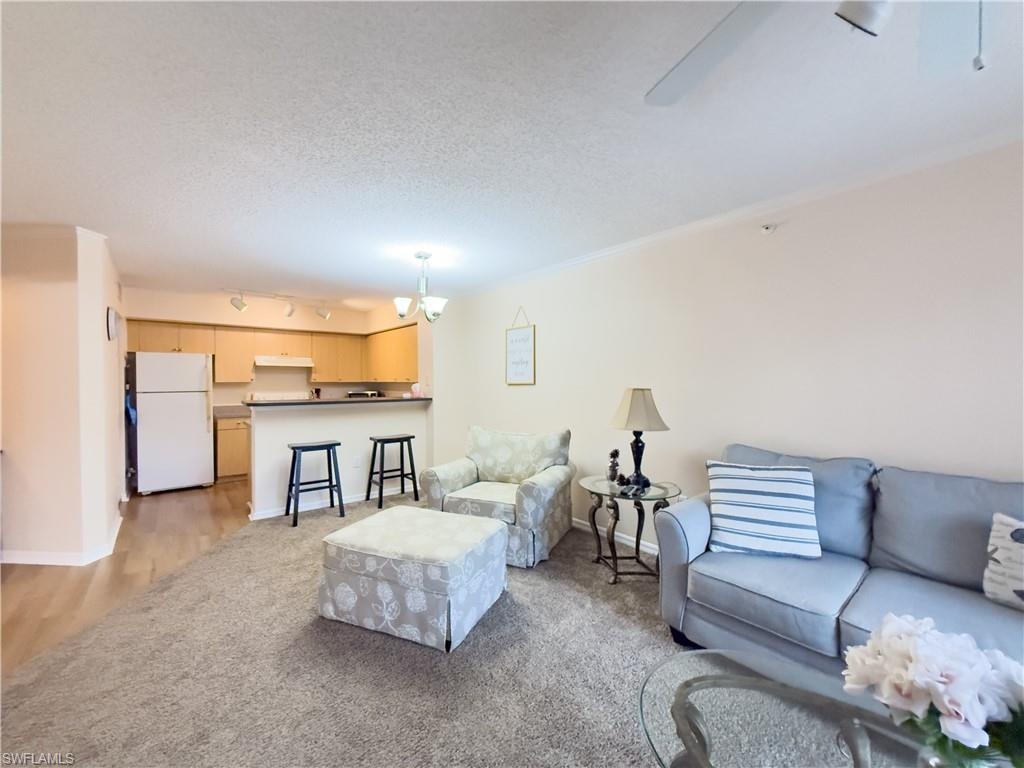 Living room with light colored carpet, rail lighting, and a textured ceiling