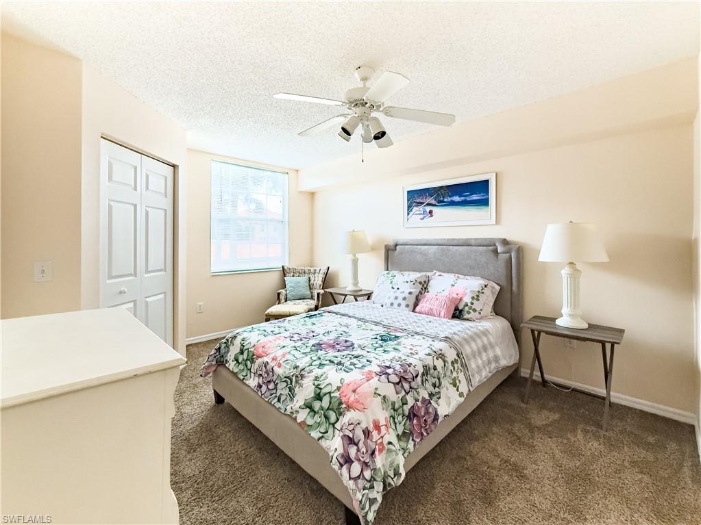 Bedroom featuring a closet, a textured ceiling, carpet flooring, and a ceiling fan