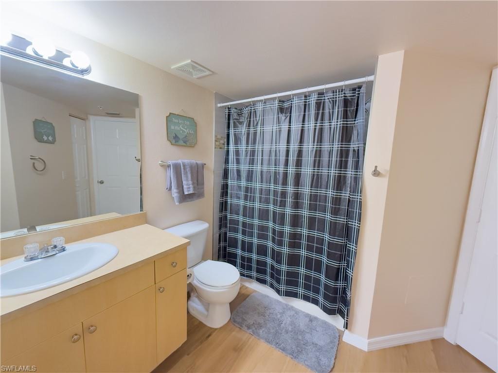 Full bathroom with wood finished floors, vanity, and a shower with shower curtain