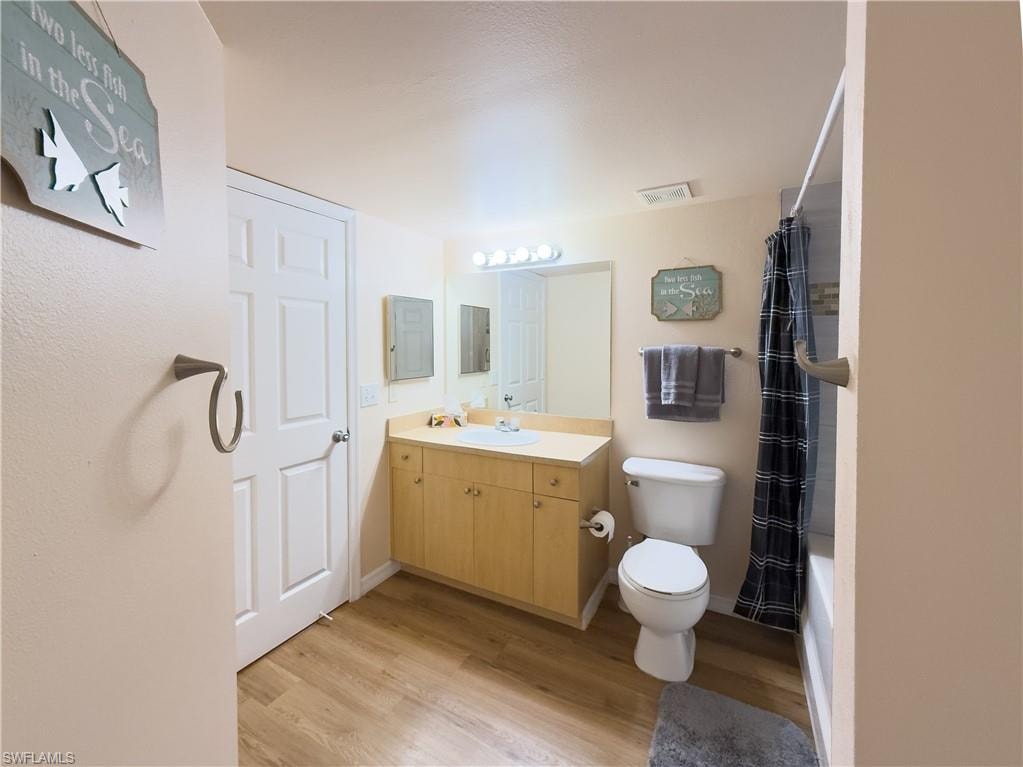 Full bathroom with vanity, wood finished floors, and shower / tub combo with curtain