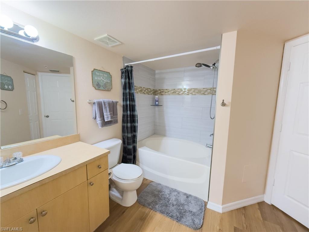 Full bathroom with shower / tub combo with curtain, vanity, and wood finished floors