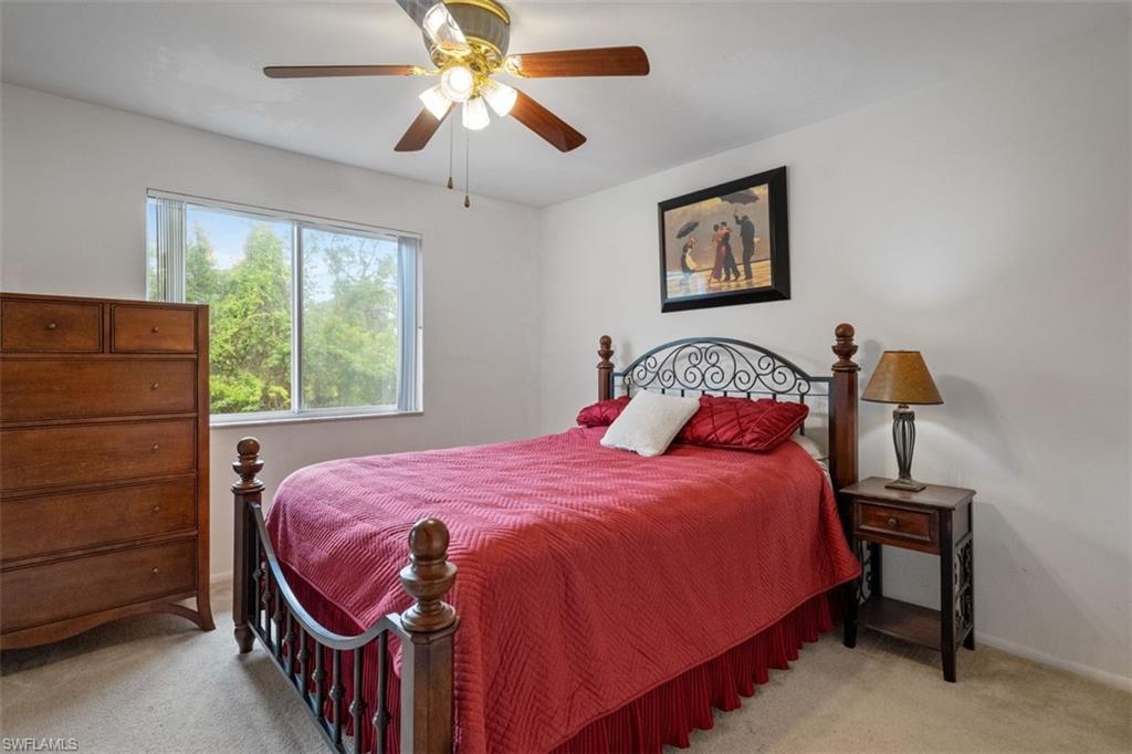 White walls, ceiling fan with integrated lighting, large window, and carpeted flooring