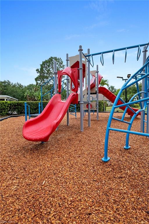 Playground area with red slides, blue monkey bars, and wood chip surfacing