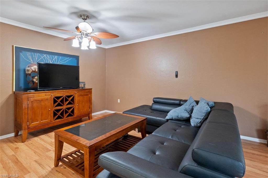 Wood-finish flooring throughout, complemented by crown molding and a ceiling fan with integrated lighting