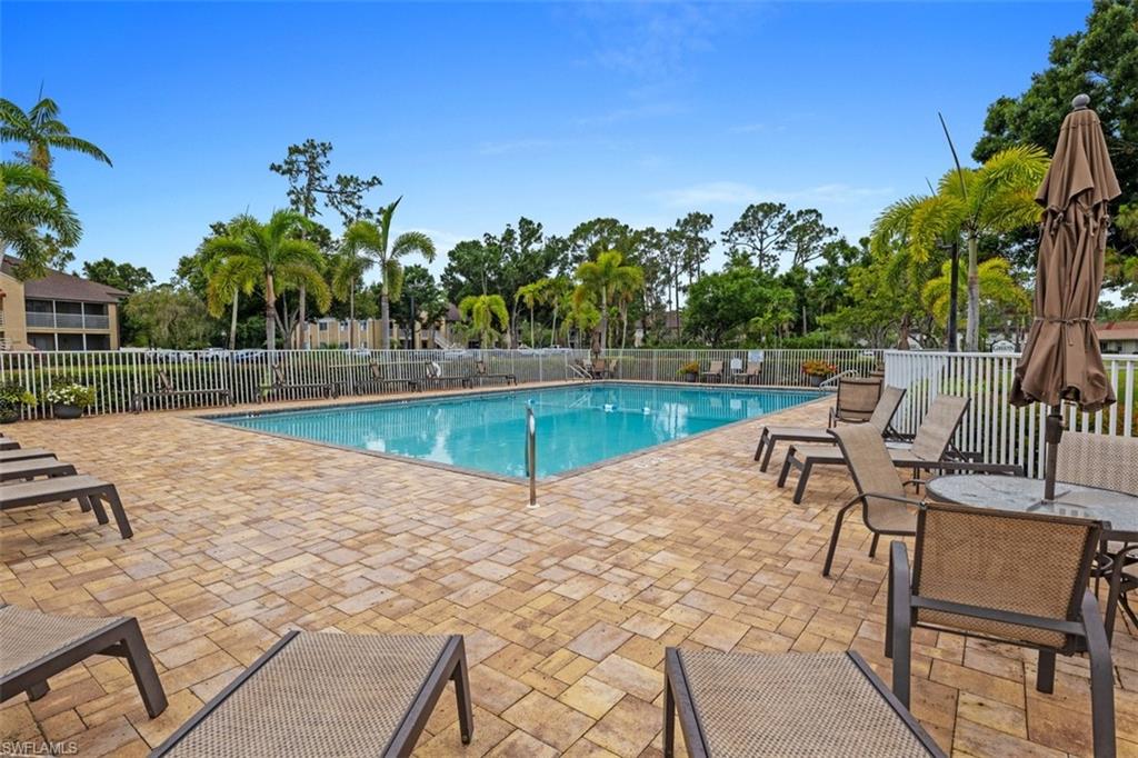 Rectangular swimming pool surrounded by a paver patio and white fencing