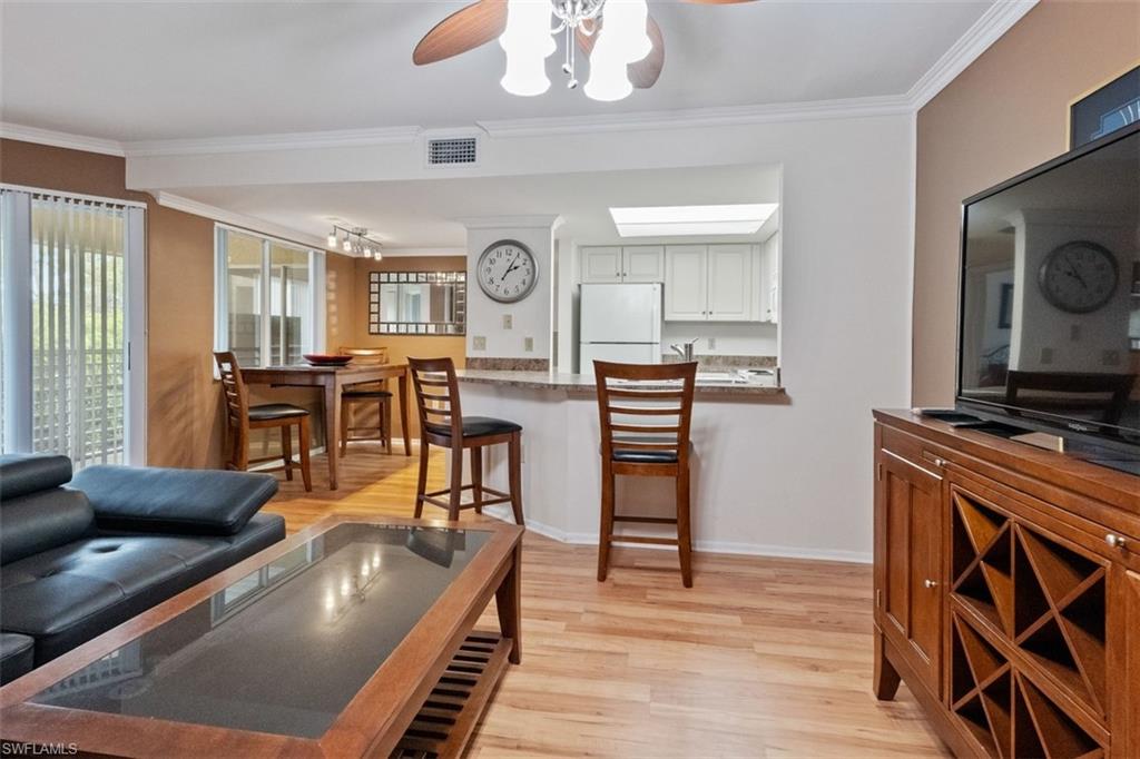 Wood-finish flooring throughout, with crown molding and an open pass-through window to the kitchen
