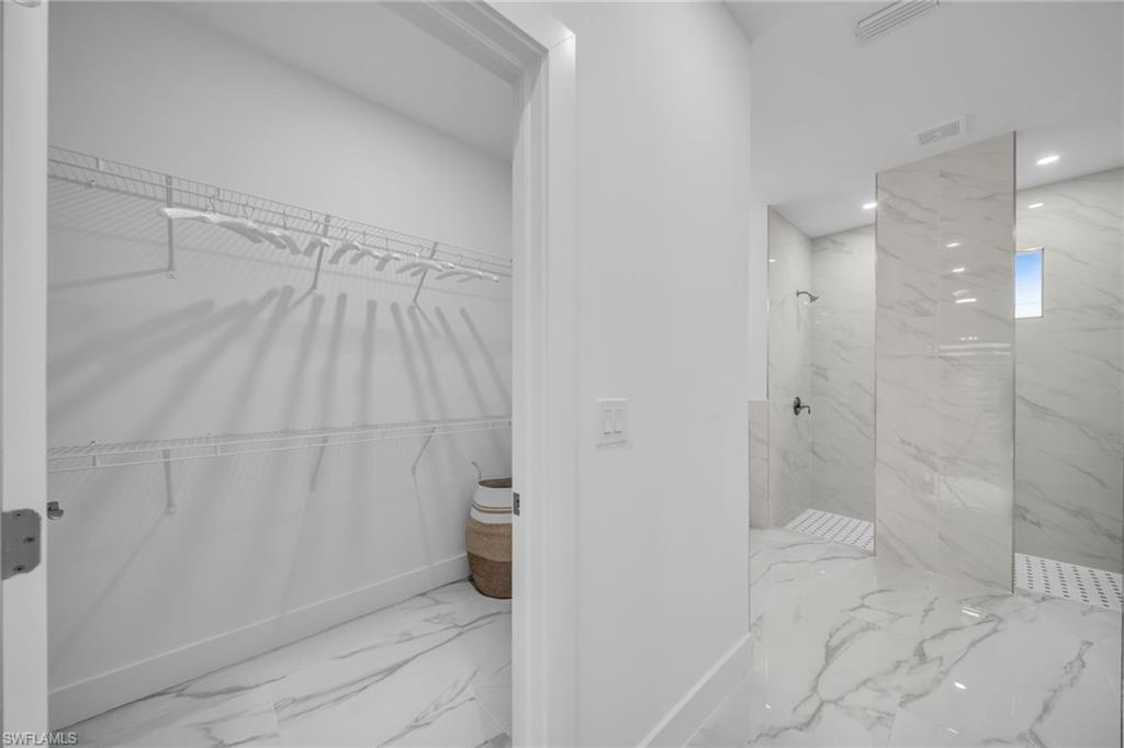 White wire shelving system, dual shower system, white tiled flooring, recessed lighting, and a window