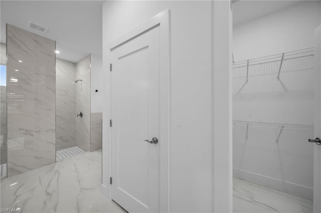 Walk-in shower with large format tile, a contrasting shower floor, and a white interior door with contemporary hardware