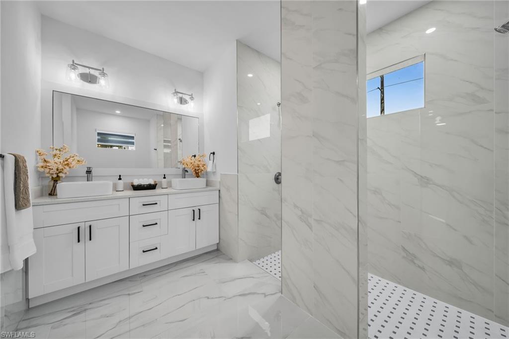 Dual vessel sinks atop a white vanity with black hardware