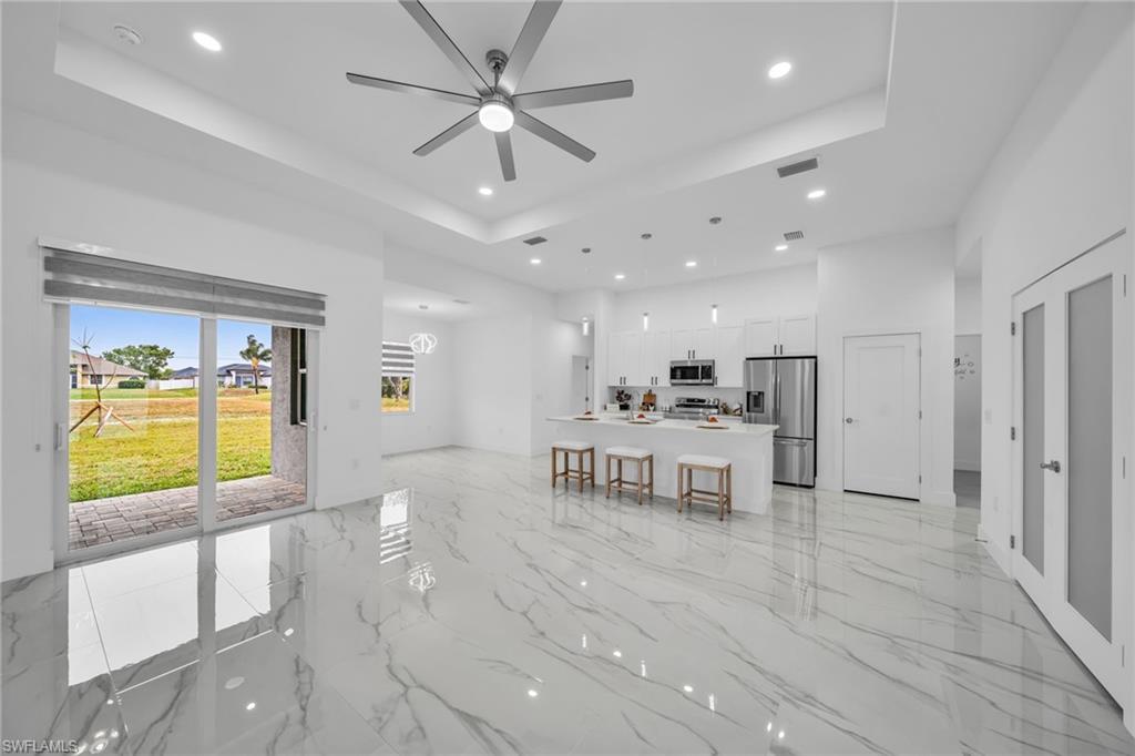 Open-concept living space featuring high ceilings, recessed lighting, large format tile flooring, and a sliding glass door leading to a patio