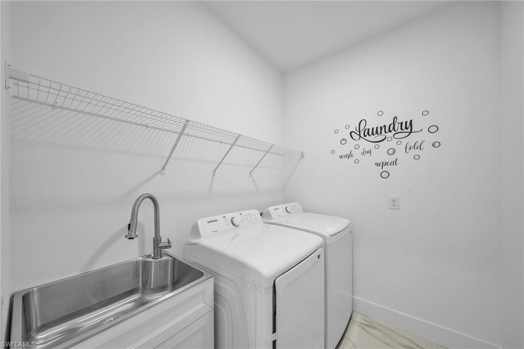 Laundry area featuring a utility sink with a gooseneck faucet, white built-in cabinetry, and wire shelving
