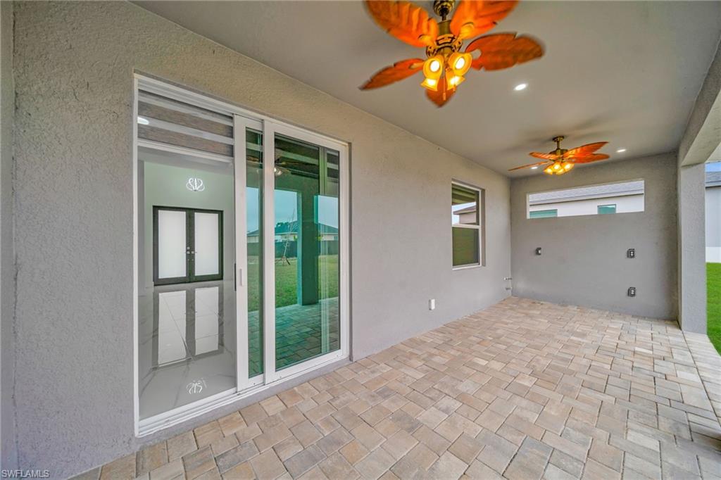 Covered patio with paver flooring, dual ceiling fans, and a sliding glass door