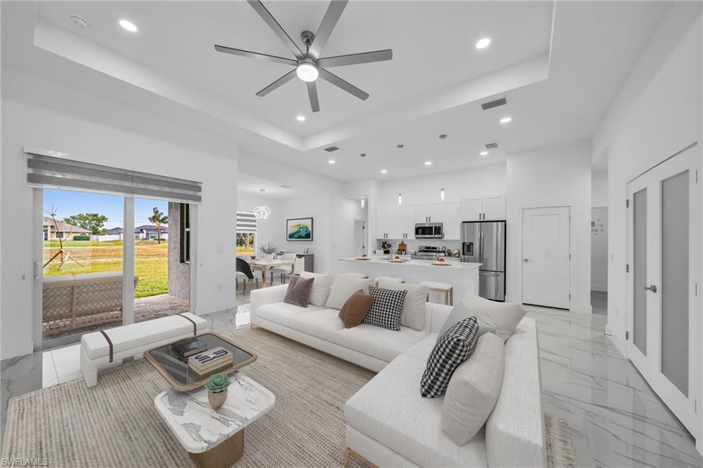 Spacious living area featuring a tray ceiling, recessed lighting, and large format tile flooring