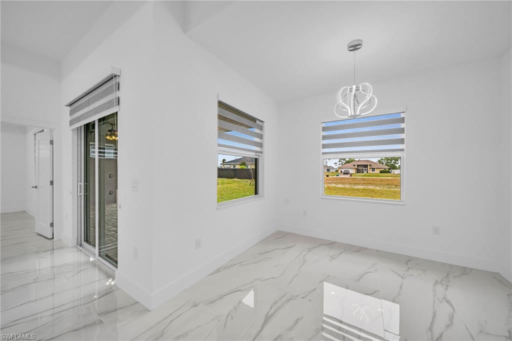 White porcelain tile flooring with grey veining, two windows with striped roller shades, contemporary chandelier, sliding glass doors, and a paneled interior door
