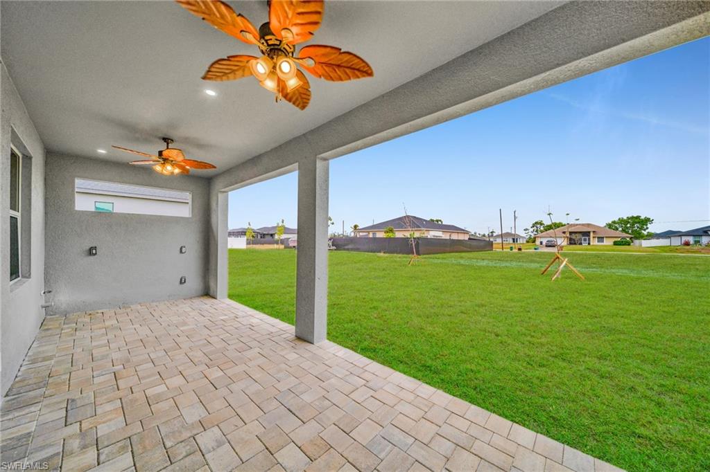 Expansive patio with paver flooring, overhead recessed lighting, and two ceiling fans