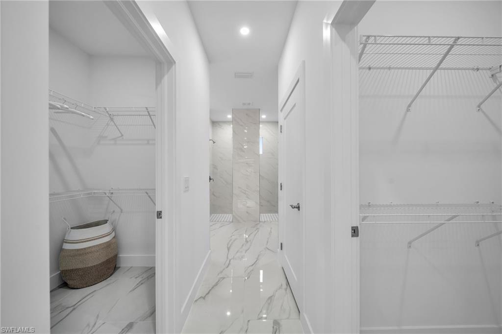 Hallway featuring polished tile flooring, recessed lighting, and two open closet spaces with wire shelving
