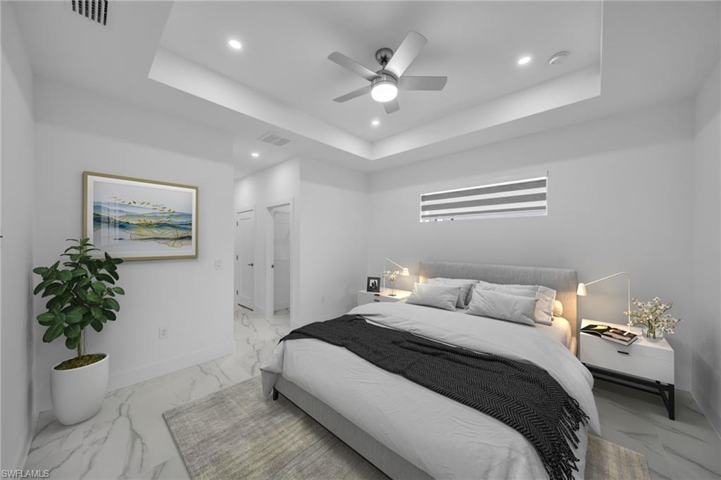 Recessed lighting, ceiling fan, tray ceiling, marble-look flooring, and a horizontal window with blinds