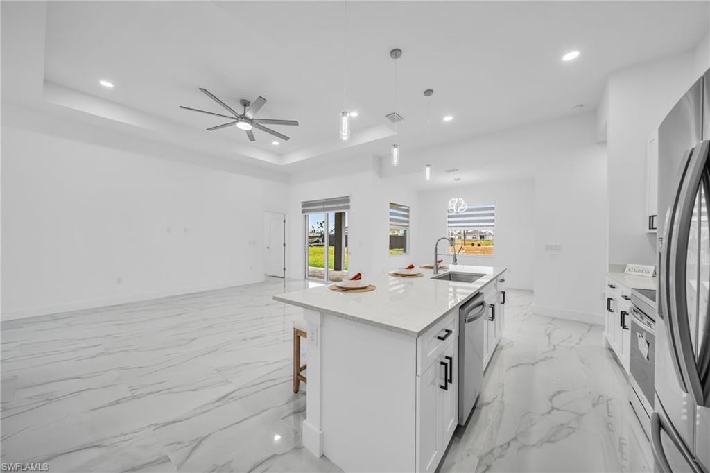 Open concept living area with tray ceiling, recessed lighting, and tile flooring