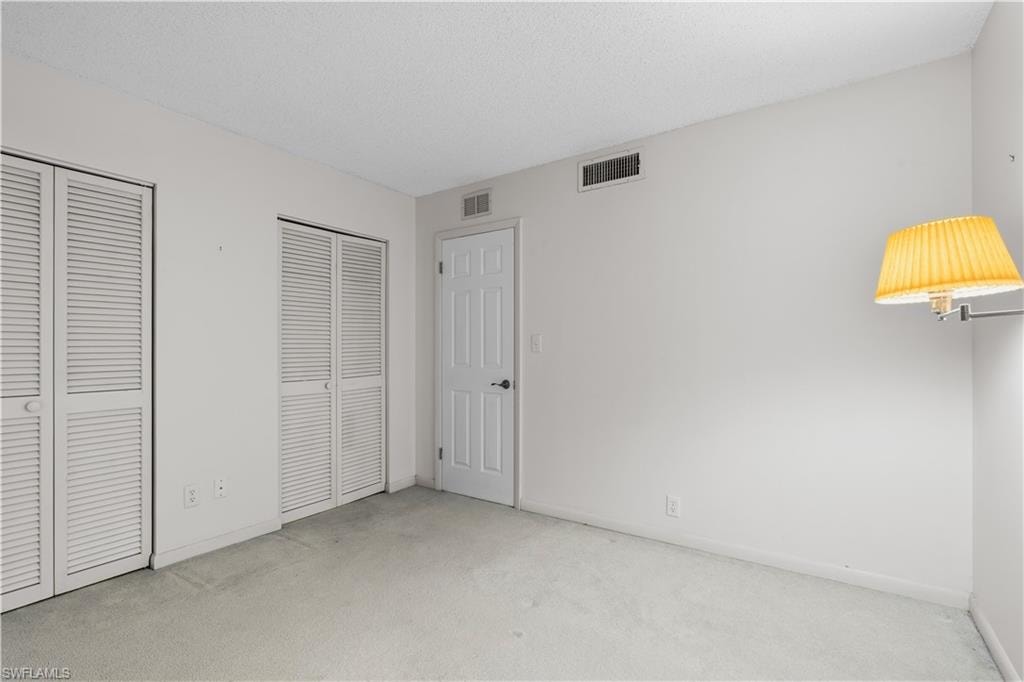 Light-colored carpeting, white walls, and a textured ceiling
