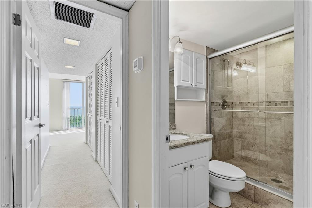 Hallway with louvered closet doors and recessed lighting