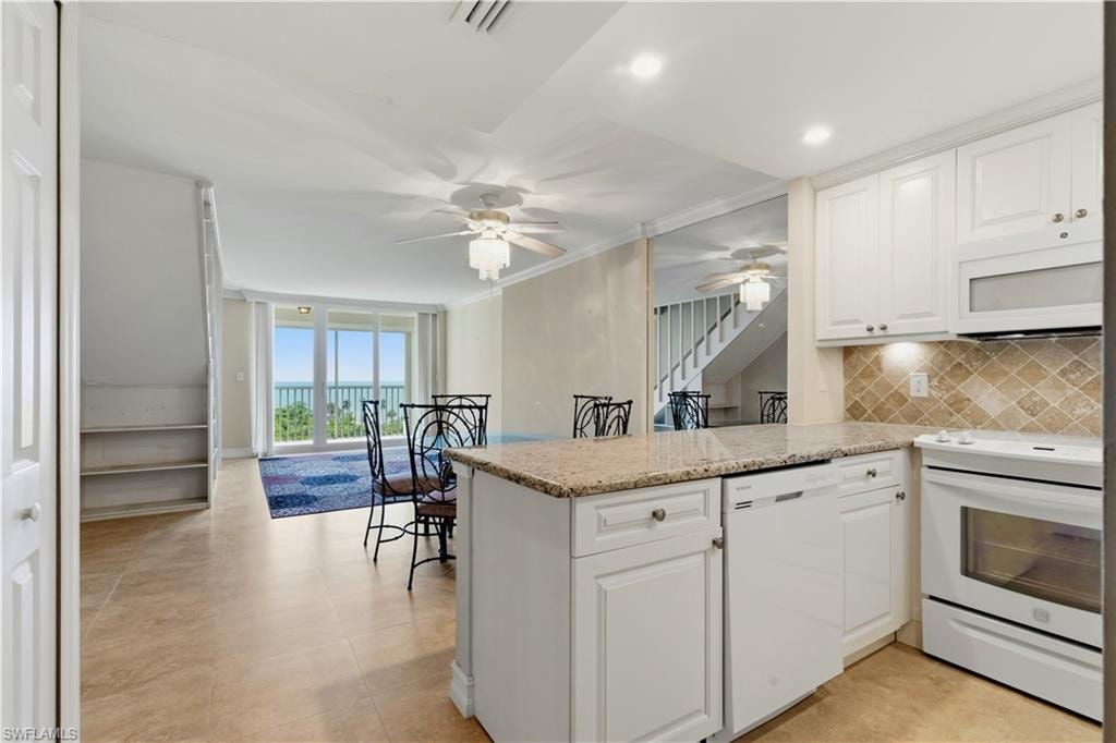 Kitchen with white cabinetry, light-toned backsplash, granite-finish countertops, and an integrated dishwasher