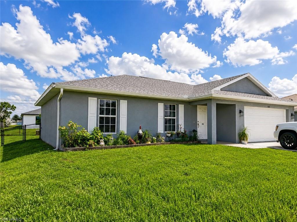 Grey stucco exterior, white garage door, white front door, white window shutters, and a well-maintained lawn