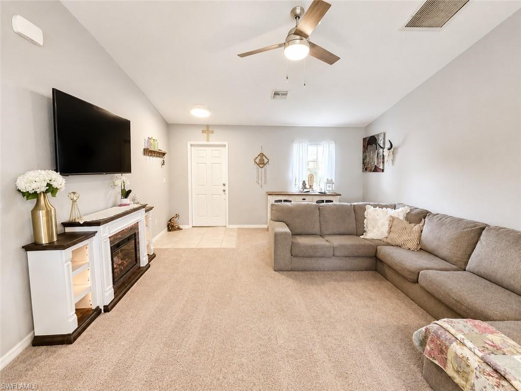 Recessed lighting, ceiling fan, fireplace with mantel and integrated shelving, carpet flooring, and tiled entryway