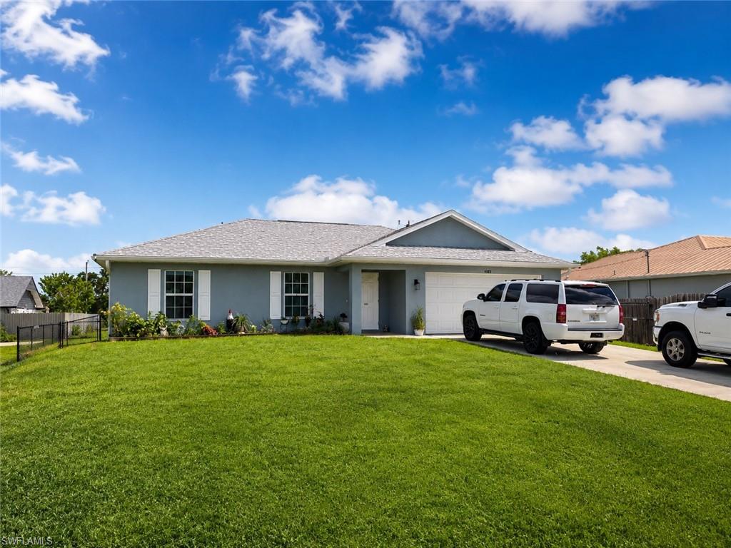 Single-story residence featuring a light blue exterior, white garage door, and a spacious front lawn