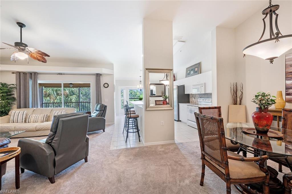 Living room with light colored carpet, light tile patterned floors, and ceiling fan
