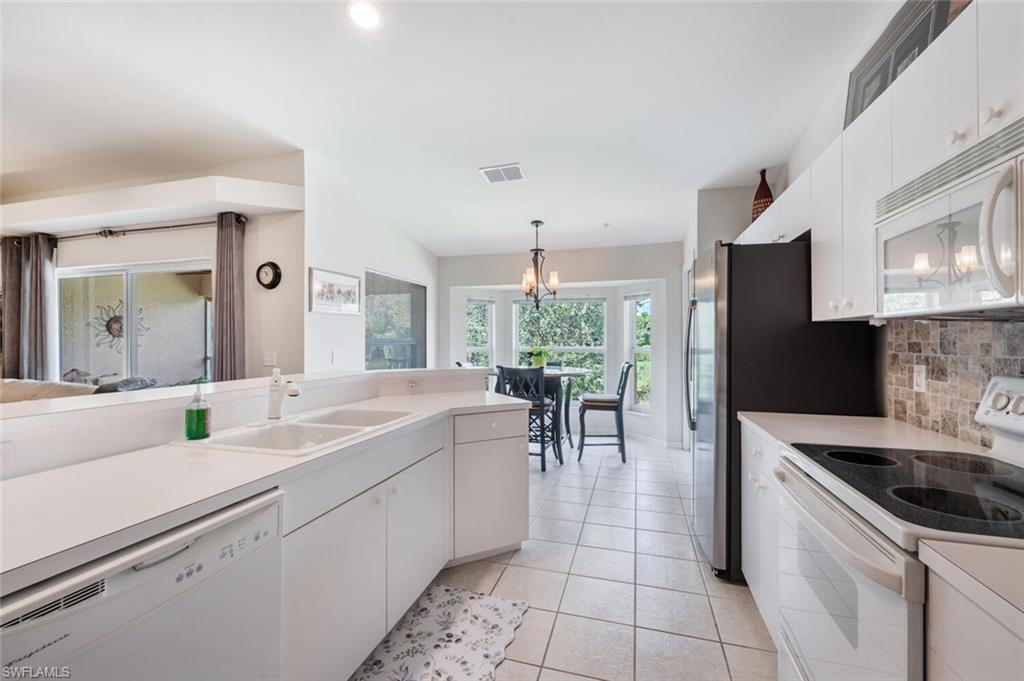Kitchen with white cabinetry, white appliances, and light countertops