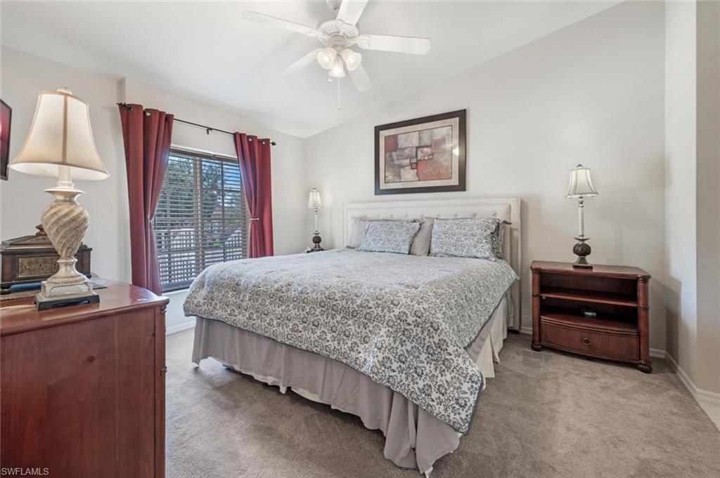 Bedroom featuring lofted ceiling, light colored carpet, and a ceiling fan