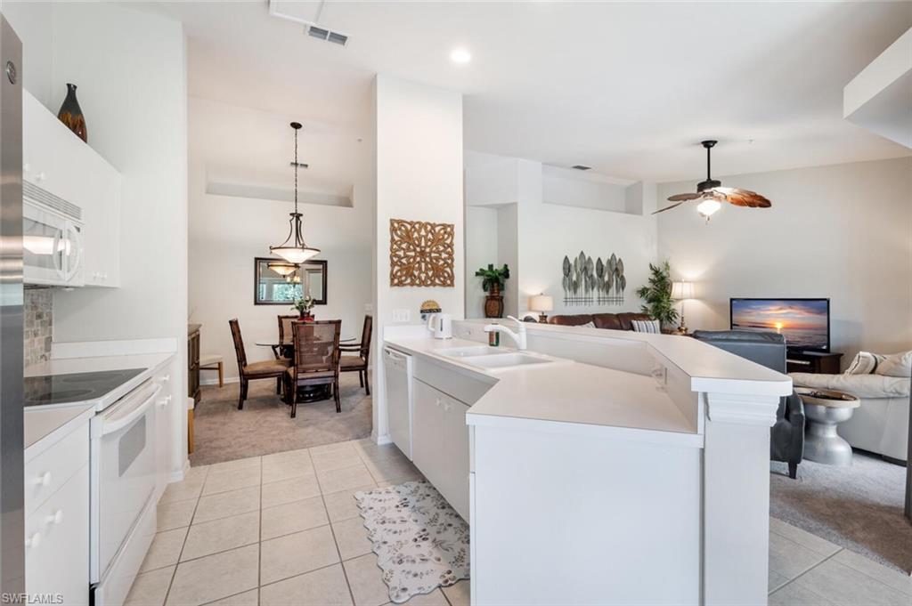 Kitchen with white cabinets, light carpet, white appliances, light countertops, and recessed lighting