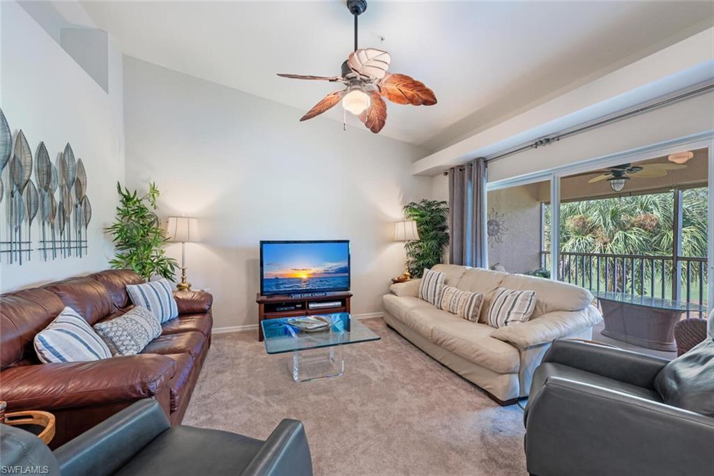 Carpeted living room with ceiling fan and vaulted ceiling