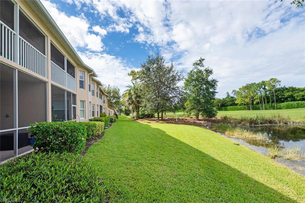 View of grassy yard with a sunroom and a water view